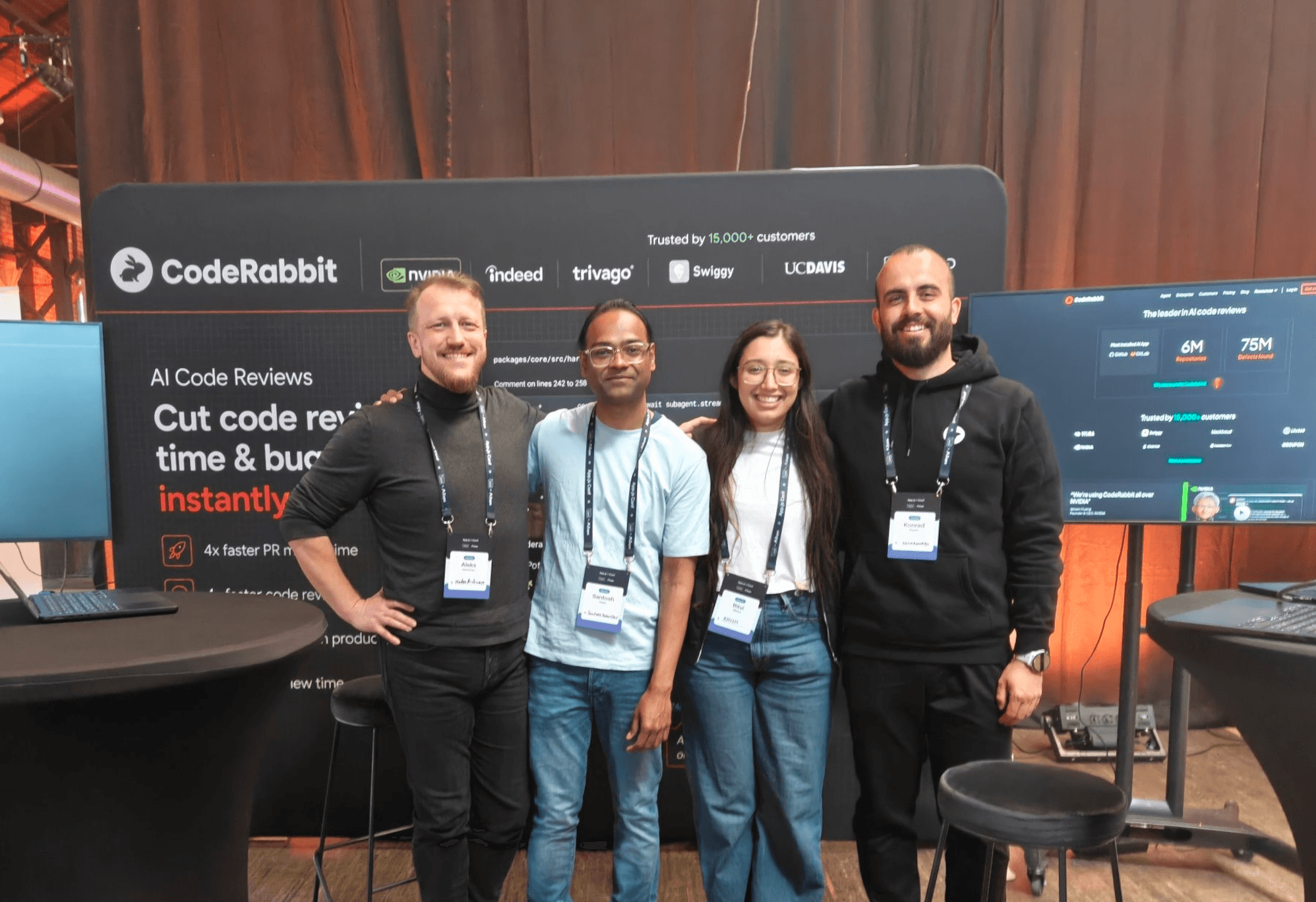 イベントでCodeRabbit AIコードレビューブースのそばに立つ、笑顔のチームメンバー4人。